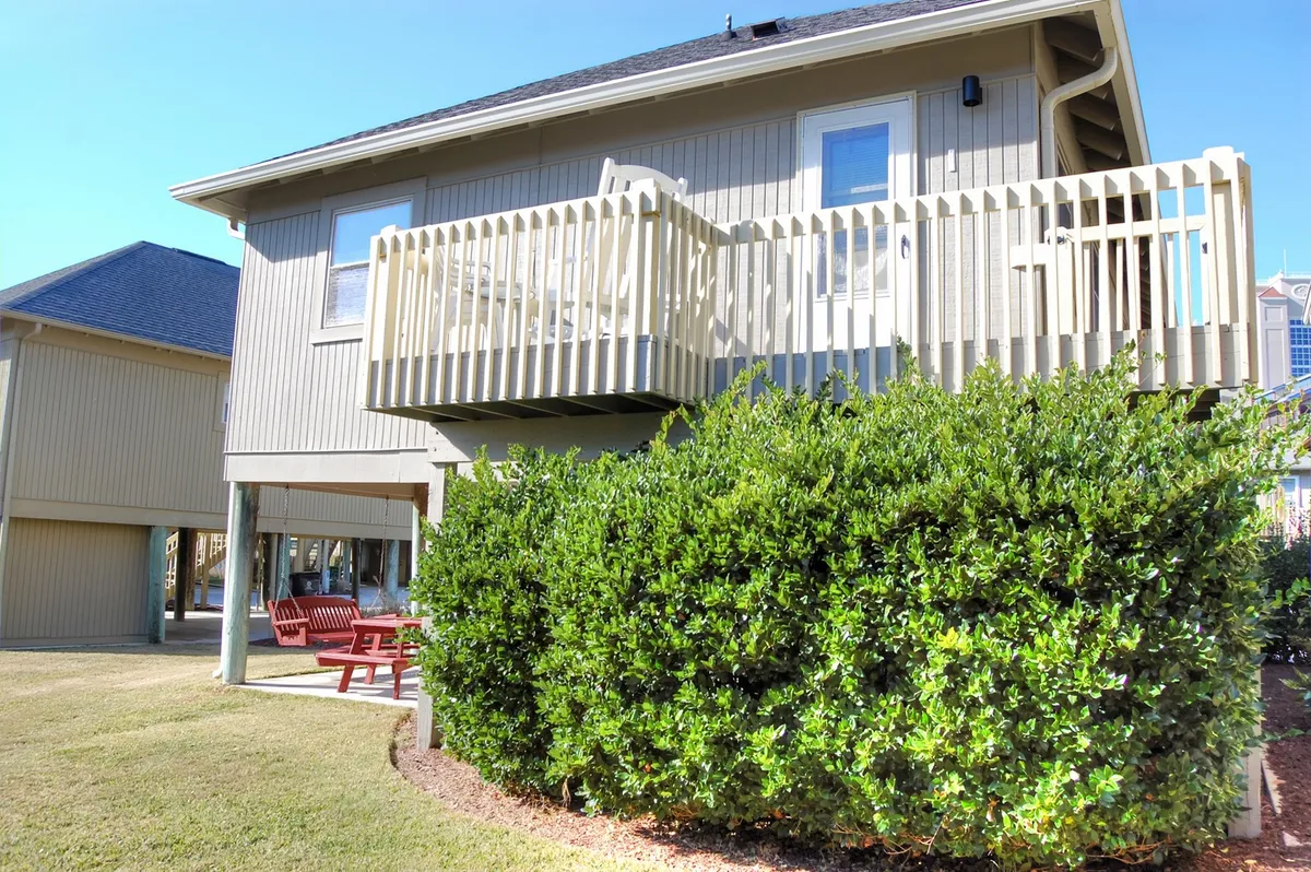 This image features the exterior of Guest Cottage 30G, highlighting its private balcony overlooking lush greenery. The balcony is outfitted with comfortable seating, perfect for relaxing, socializing, or enjoying meals outdoors. The scene radiates a welcoming mood with sunset lighting and a sense of tranquility.