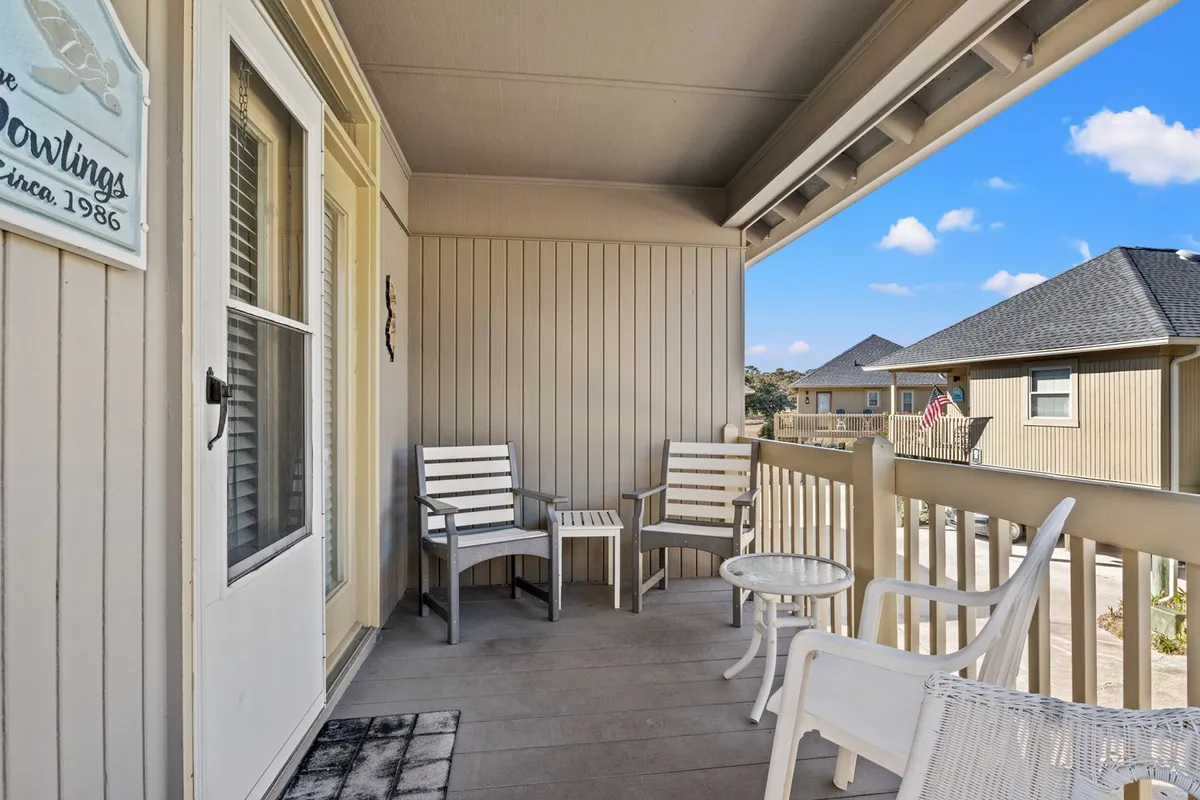 This exterior shot features a peaceful seating area with white chairs and a table outside the cottage's doorway. The space is inviting, offering a tranquil setting for morning coffee or evening relaxation, with hints of the surrounding landscape visible.