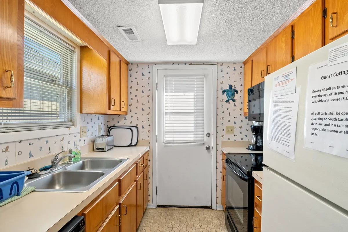 This image shows a spacious, inviting kitchen featuring a prominent counter, a sink, and a stove. There is a door leading outside, suggesting the kitchen’s central location within the home. The space is well-lit and organized, ideal for meal preparation and gathering with family.